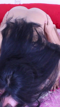 Napalona Ladyboy bawi się na łóżku ubrana w czerwoną bieliznę.