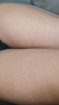 Une femme avec beaucoup de beaux cheveux pubiens entre ses jambes se couche sur son canapé en attendant qu’on lui soit fait l’amour