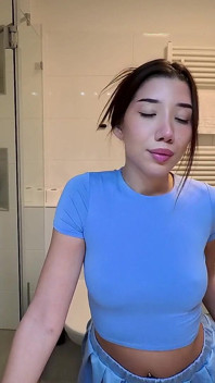 Une petite beauté brune sexy en mini-jupe la plus courte enlève sa culotte pour exhiber sa chatte étroite et son cul nu