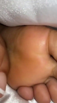 Chica de ébano debajo de sus cubre en la cama muestra los pies