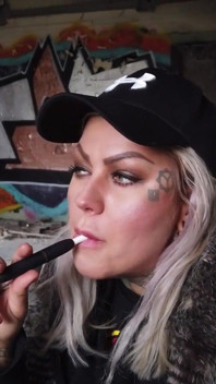 Blond dama pali elektronicznego papierosa na schodach