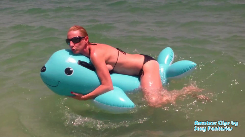 Brittany Lynn: Transando com brinquedo inflável azul na água em uma praia até...