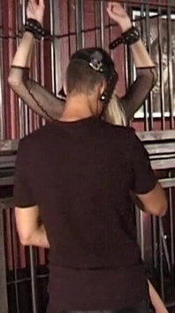 Mature Dominatrix Oversees Masked Man with Bound Blonde