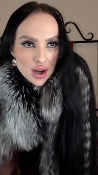 Bimbo en abrigo de piel juega con consolador y muestra la lengua