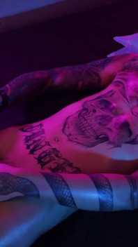 Twink tatuado caliente sacudiendo su gran polla sin cortar con aceite y disparando su semen