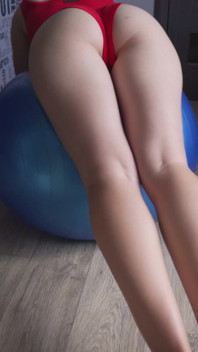 Fitness dívka v červeném obleku poskakuje na cvičebním míči