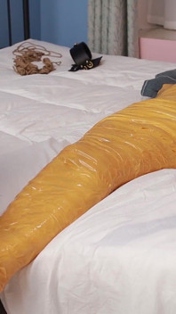 Una dolce ragazza scalza usa del nastro adesivo per legare tutto il corpo, giocando con i suoi carini piedi nudi