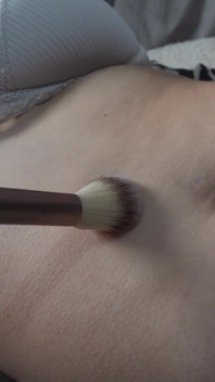 Latina meisje speelt met haar buik en navel met haar vingers en speelt er dan mee met een verfborstel