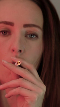 Une petite brune fume en gros plan