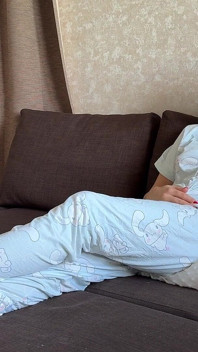 в пижаме на подушке, сидя на диване