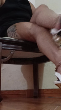 Her Long Legs Are Crossed, and Her High Heels Dangle From Her Feet as She Sips a Delicious Cup of Coffee