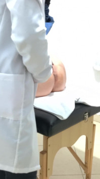 Proktolog provádí anální vyšetření kondomovaného pacienta