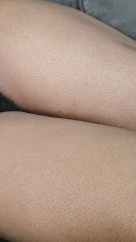 Uma mulher com muitos pelos púbicos bonitos entre as pernas está em seu sofá esperando para ser feita amor para ela