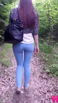 Desperate Brunette with Long Legs in Tight Jeans Walking Trough Forest Searching for a Place to Pee