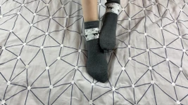 Flicka med långa ben smeker fötterna i grå nyårsstrumpbyxor med hjort