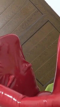 Una ragazza arrapante in tuta di lattice rosso pompa il cazzo di un grosso ragazzo