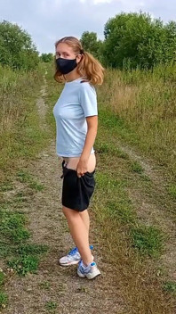 Bottomless girl with pigtails walks along a country road