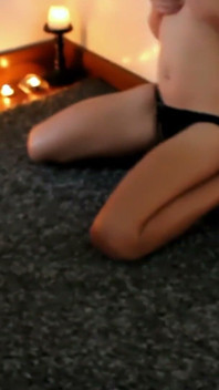 Spogliarello con candela sul pavimento - bellezza dai capelli scuri in lingerie nera si tocca