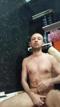 Um homem nu masturba seu pau grande no banheiro