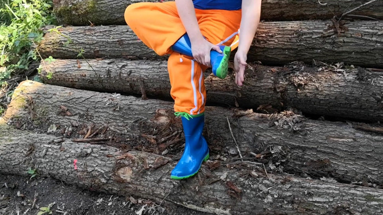 Bouncy Tits Action: Sitting in rubberboots on woodpile