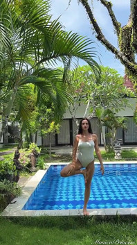 Pose y provoca en un árbol de yoga al aire libre en traje transparente en la piscina