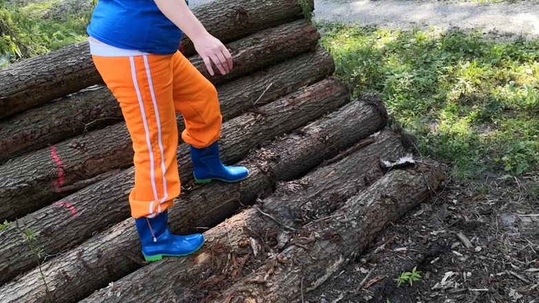 Bouncy Tits Action: Sitting in rubberboots on woodpile