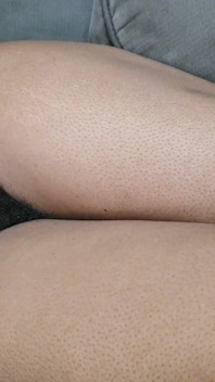 Uma mulher com muitos pelos púbicos bonitos entre as pernas está em seu sofá esperando para ser feita amor para ela
