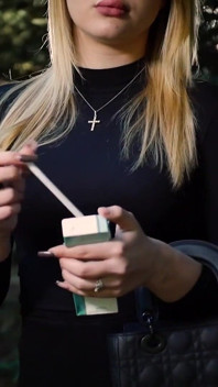 Nena rubia caliente fumando un cigarrillo negro en la naturaleza
