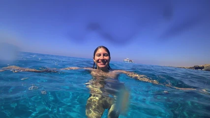 Una splendida ragazza nuota nuda sulla spiaggia pubblica