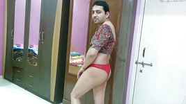 Sexy sissy crossdresser femboy sweet lízátko v tištěném topu, červené tanga a saténové pantofle.