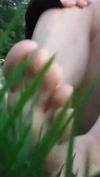 Jon Arteen en short court marche sur l’herbe pieds nus, montre les dessous de pieds de son garçon, sourit pour vous