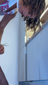Linda y hermosa chica universitaria de ébano en pantimedias muestra en la cocina después de aburrirse e ignorada