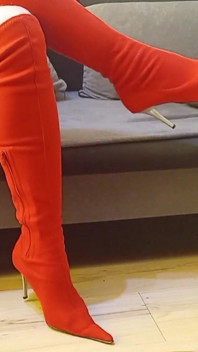 Seksi kırmızı süet ayak parmaklı yüksek topuklu çizmeler içinde travesti sallanıyor