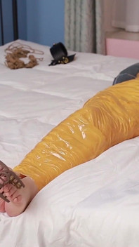 Une petite amie mignonne pieds nus utilise du ruban adhésif pour attacher tout son corps, jouant avec ses jolis pieds nus