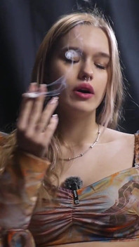 Dulce rubia rusa fumando en blusa colorida