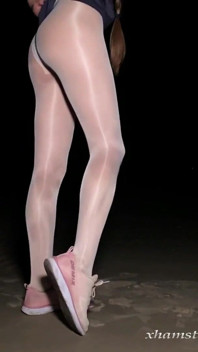 Anna in collant bianchi lucidi sulla spiaggia di notte