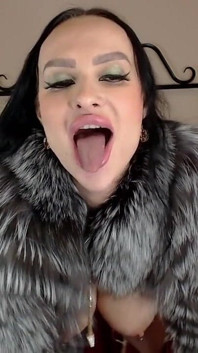 Bimbo in bontjas speelt met dildo en toont tong