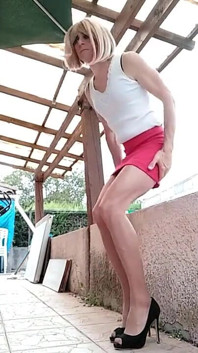 Tacchi alti bionda sexy travestito transessuale con gonna rossa all'aperto