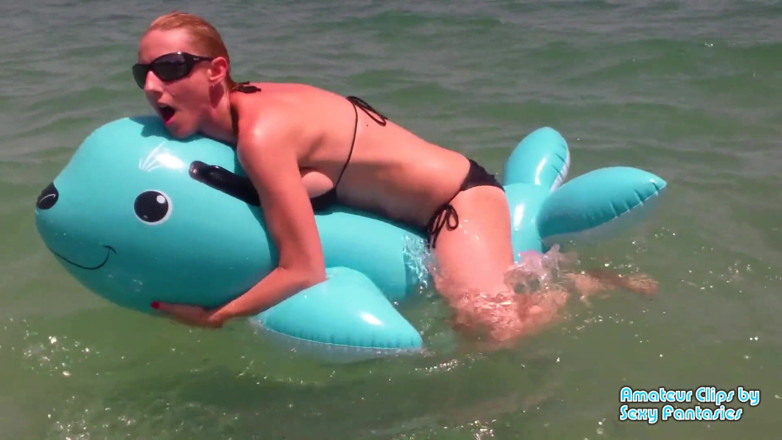 Brittany Lynn: Vögelndes blaues aufblasbares spielzeug im wasser an einem strand bis...