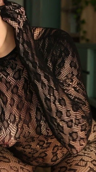 Estoy posando en un traje de rejilla negro y tacones, complacándome con mis dedos