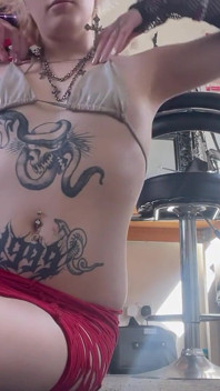 Goth Dziewczyna dotyka guzika brzucha i bawi się kolczykiem pępka