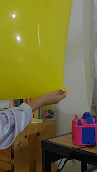 Marianna tenta inflar seu balão quadrado sem explodi-lo
