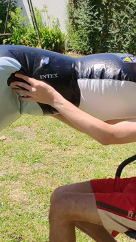 Un bel homme gonfle sa baleine gonflable près de la piscine à l’extérieur