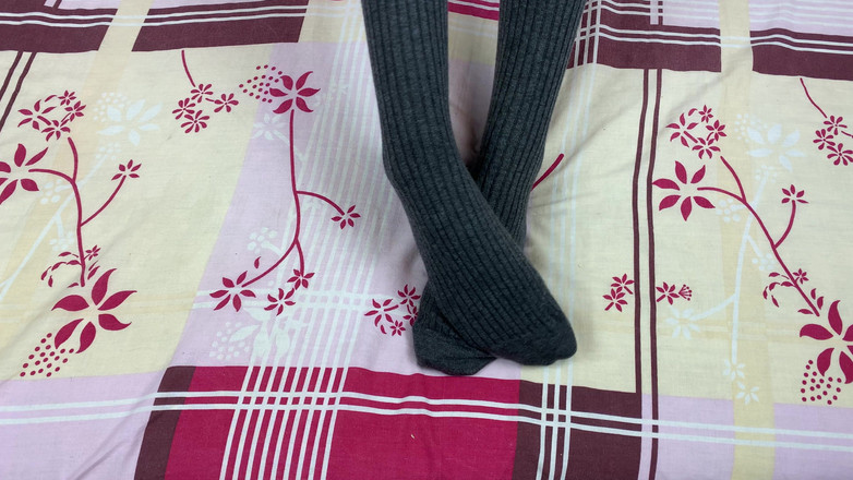 Gloria Gimson: Fată în șosete gri lungi pe picioare se mângâie în pat