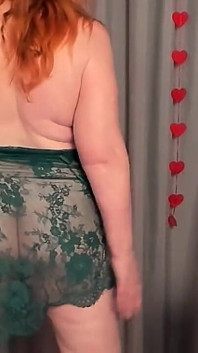 Rijpe roodharige dame 50+ striptease in transparante smaragdgroene jurk