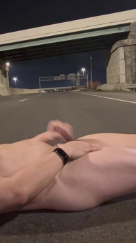 밤에 빈 도로의 한가운데로 걷는 벌거벗은 근육진 아시아인, 열심히 구부리고 엄청난 짐을 쏴