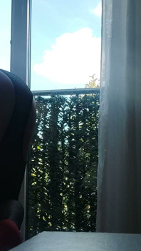 In dessous und High Heels am Fenster mit einem Spielzeug