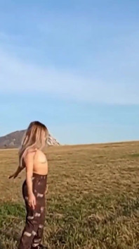Uma garota com um corpo bonito posa em um campo