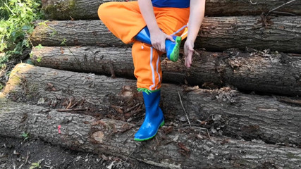 Bouncy Tits Action: Sitting in rubberboots on woodpile