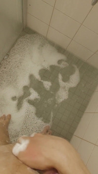 Un jeune garçon blanc et mince sous la douche pisse et éjacule